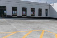 an empty parking lot with a train parked nearby and people walking by the door to the station