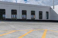 an empty parking lot with a train parked nearby and people walking by the door to the station