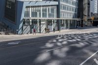 people walking on the sidewalk in front of a building with lots of glass doors and windows