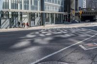 people walking on the sidewalk in front of a building with lots of glass doors and windows