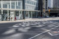 people walking on the sidewalk in front of a building with lots of glass doors and windows