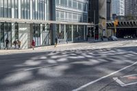 people walking on the sidewalk in front of a building with lots of glass doors and windows