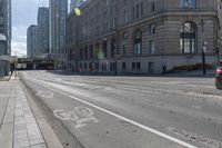 a street with an empty roadway and buildings in the background is a bus lane that has white stripes