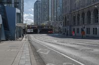 a street with an empty roadway and buildings in the background is a bus lane that has white stripes