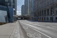 a street with an empty roadway and buildings in the background is a bus lane that has white stripes