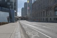 a street with an empty roadway and buildings in the background is a bus lane that has white stripes