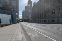 a street with an empty roadway and buildings in the background is a bus lane that has white stripes