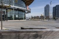 an empty parking lot with benches and wooden posts in front of it in front of tall buildings