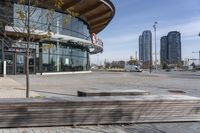 an empty parking lot with benches and wooden posts in front of it in front of tall buildings