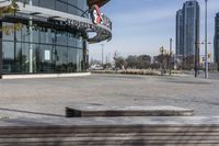 an empty parking lot with benches and wooden posts in front of it in front of tall buildings