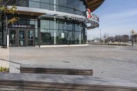 an empty parking lot with benches and wooden posts in front of it in front of tall buildings