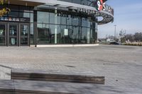 an empty parking lot with benches and wooden posts in front of it in front of tall buildings