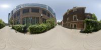 a person taking a picture with the fisheye lens of a building in the background