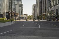 a view down the street of some tall buildings and cars in the distance, and on which a bus and a man