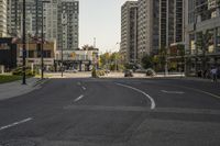 a view down the street of some tall buildings and cars in the distance, and on which a bus and a man