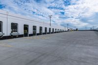 a parking lot with two doors and a white building in the back ground and the sky behind it