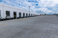 a parking lot with two doors and a white building in the back ground and the sky behind it