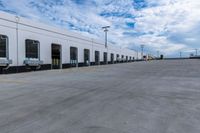 a parking lot with two doors and a white building in the back ground and the sky behind it