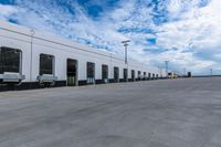 a parking lot with two doors and a white building in the back ground and the sky behind it