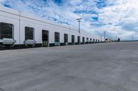 a parking lot with two doors and a white building in the back ground and the sky behind it