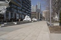 a long walkway with a white sculpture near some tall buildings and trees in the city