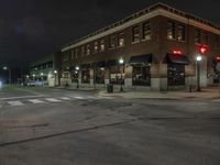 an empty city street with buildings and a traffic light at night time a red light shines above the building