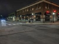 an empty city street with buildings and a traffic light at night time a red light shines above the building