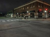 an empty city street with buildings and a traffic light at night time a red light shines above the building