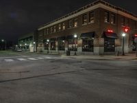 an empty city street with buildings and a traffic light at night time a red light shines above the building