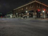 an empty city street with buildings and a traffic light at night time a red light shines above the building