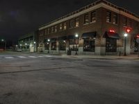 an empty city street with buildings and a traffic light at night time a red light shines above the building