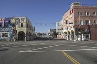 a large white sign hanging in the middle of a road with buildings and cars behind it