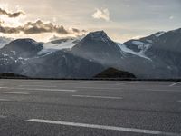 a picture of the mountains are behind the road as the man walks on the road