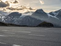 a picture of the mountains are behind the road as the man walks on the road