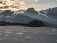 a picture of the mountains are behind the road as the man walks on the road