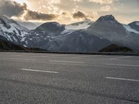 a picture of the mountains are behind the road as the man walks on the road