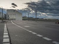 a cloudy view of an empty road between buildings with a person riding a skateboard on it