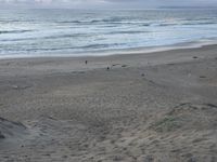 people are on a beach looking out into the ocean or the ocean from the sand