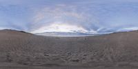 the picture shows a sandy field and ocean from a perspective lens in the sky by itself