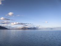 the large body of water in the open field on a sunny day, with small clouds above mountains