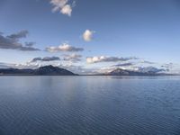 the large body of water in the open field on a sunny day, with small clouds above mountains