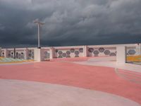 the concrete walkway and sky is very dramatic in this photo the street is painted pink