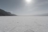 view of a salt flat landscape during the day with sun in middle of the scene