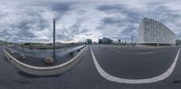 the image is in fisheye mode with a cloudy sky above it and on this side, there are street lined with road signs