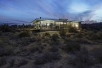 an image of a glass house lit up in the sun at dusk in the desert