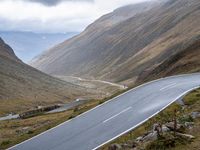 a motorcycle is going on the road through mountains and mountains in the distance are parked cars