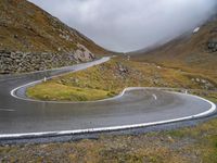 a curve in the middle of a mountain road with a motorcycle in the middle and an umbrella on a tripod