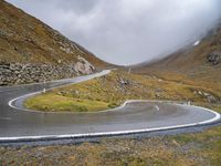 a curve in the middle of a mountain road with a motorcycle in the middle and an umbrella on a tripod