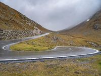 a curve in the middle of a mountain road with a motorcycle in the middle and an umbrella on a tripod