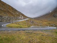 a curve in the middle of a mountain road with a motorcycle in the middle and an umbrella on a tripod